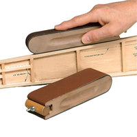 Wooden model airplane with sandpaper being used to smooth a part of the model.