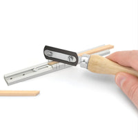 Hand holding a tool with wooden handle and metal components on a white background